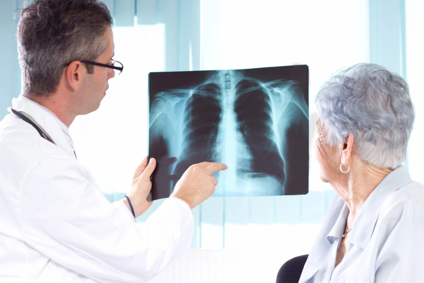 A doctor pointing to an x-ray of someone 's chest.